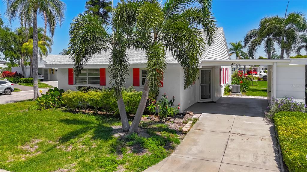 A white single-story house with red shutters, a palm tree, and a concrete driveway — 4523 W INDEPENDENCE DRIVE, BRADENTON, FL