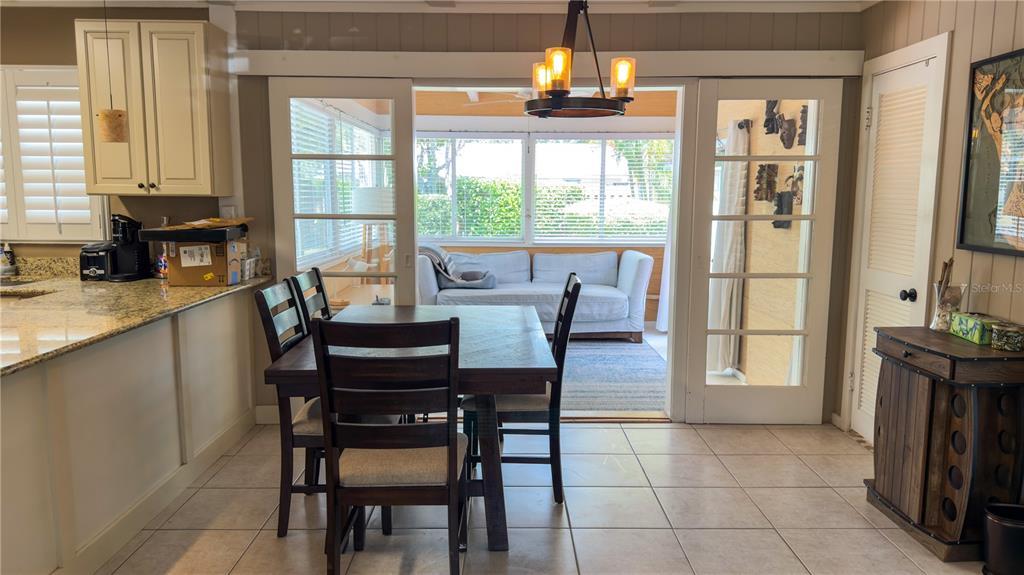 A dining area with a wooden table and chairs sits before a sunroom with windows — 2475 W PAULSTAN COURT, SARASOTA, FL