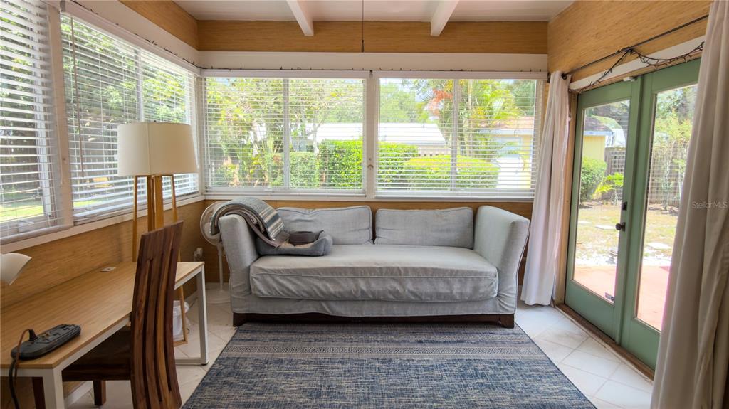 A sunroom features a light gray sofa, a wooden desk, and large windows with blinds — 2475 W PAULSTAN COURT, SARASOTA, FL
