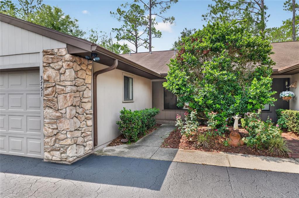 A house exterior features a stone-faced garage, a concrete walkway, and a landscaped front yard — 3751 NW 53RD ROAD, GAINESVILLE, FL