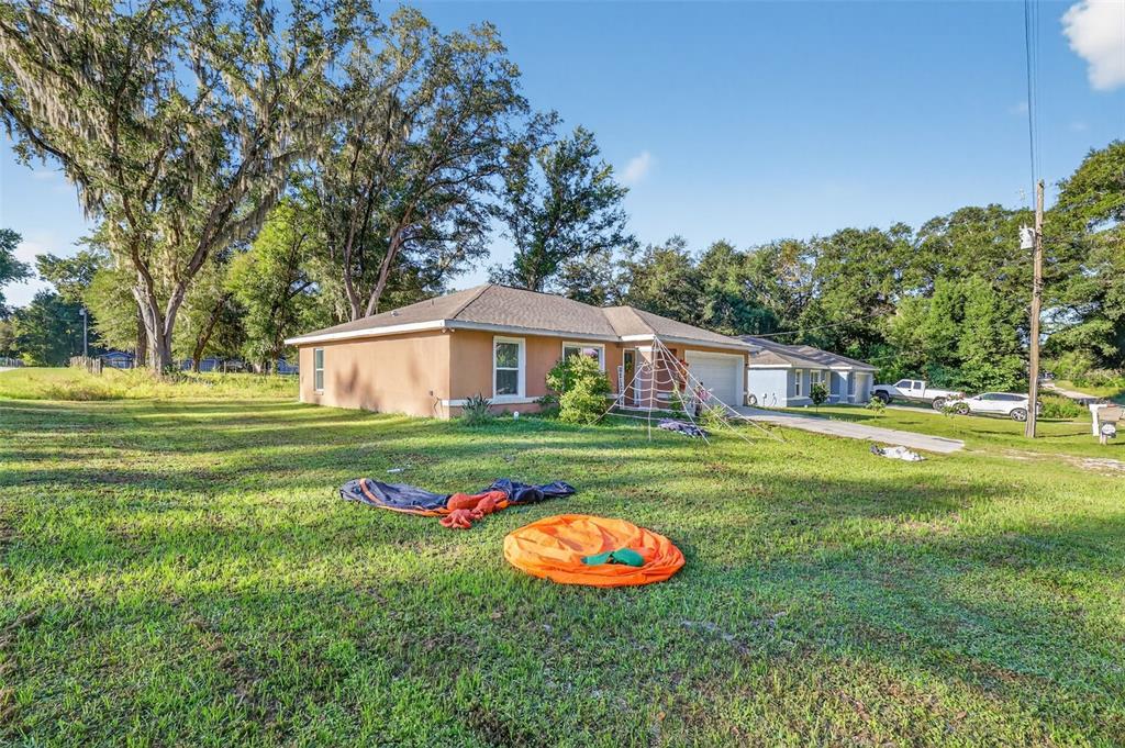 A single-story house with a tan exterior and a spiderweb decoration on the front lawn — 3062 SE 141ST PLACE, SUMMERFIELD, FL