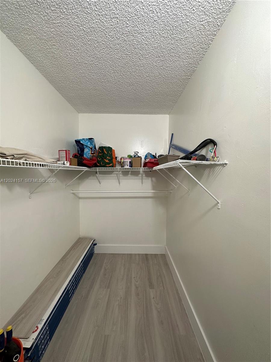 A walk-in closet features white walls, a popcorn ceiling, wire shelving, and light-colored wood-look flooring — 10813 NW 7th St # 11, Miami FL 33172, MIAMI, FL