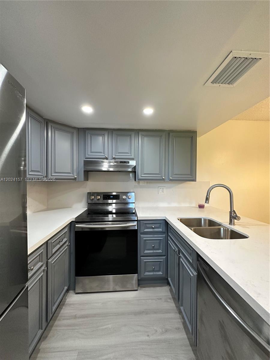 A kitchen features gray cabinets, white countertops, stainless steel appliances, and light wood-look flooring — 10813 NW 7th St # 11, Miami FL 33172, MIAMI, FL