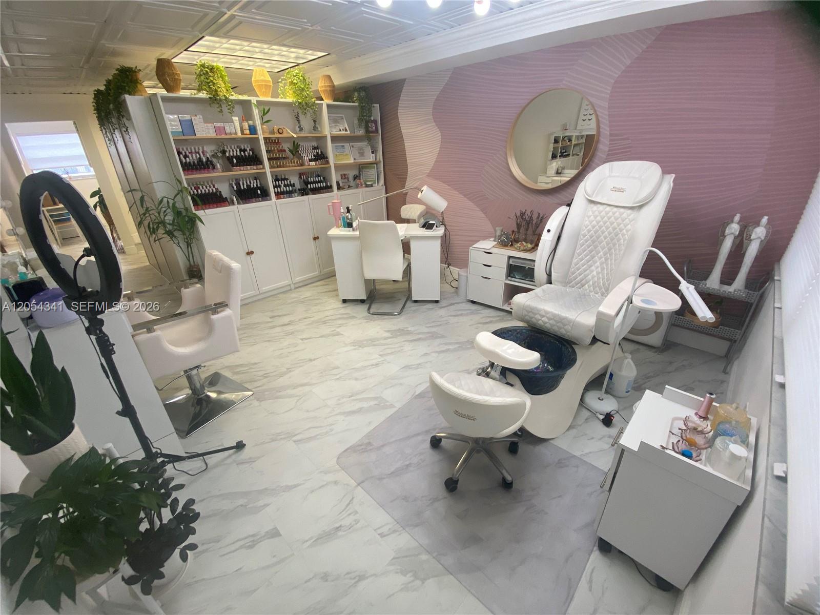 A salon room features a pedicure chair, manicure station, shelving, and pink accent wall — CORAL GABLES, FL