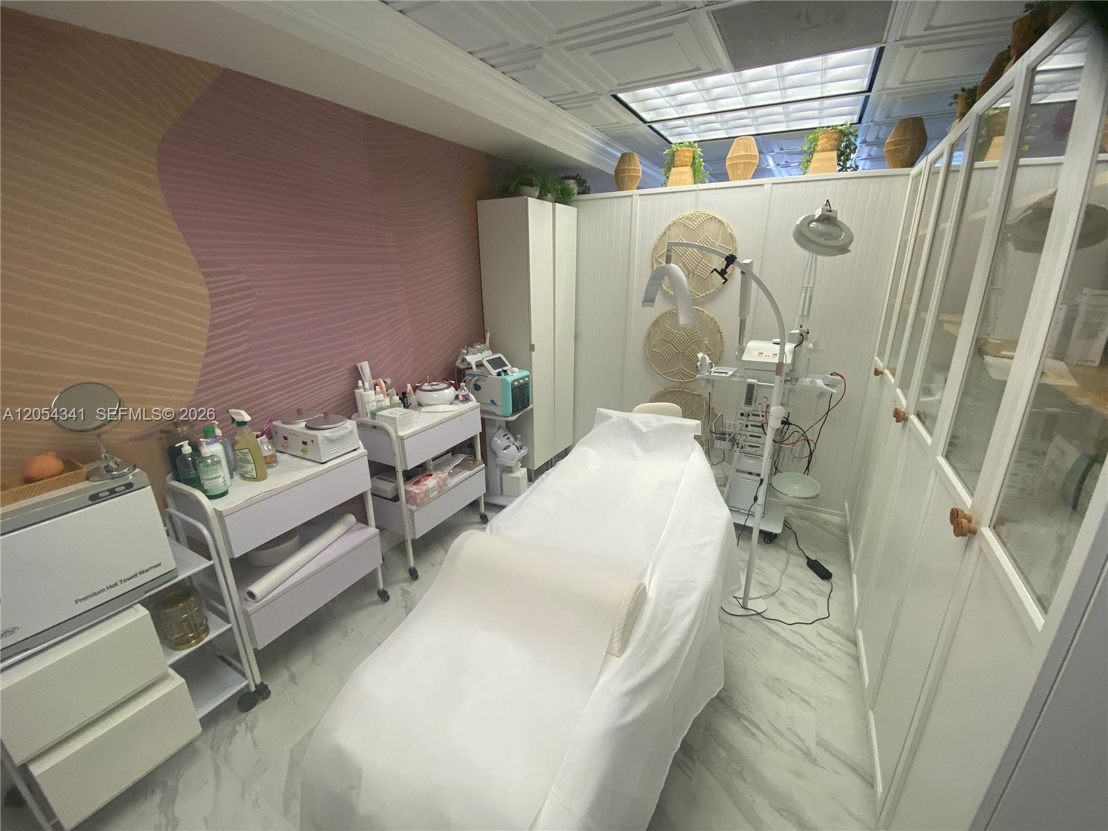 A small treatment room features a massage bed, medical equipment, and white storage cabinets — CORAL GABLES, FL