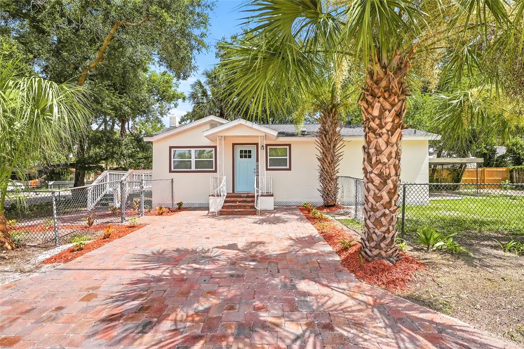 A single-story house with a brick paver driveway, light-colored siding, and two palm trees — 1002 E SEWARD STREET, TAMPA, FL