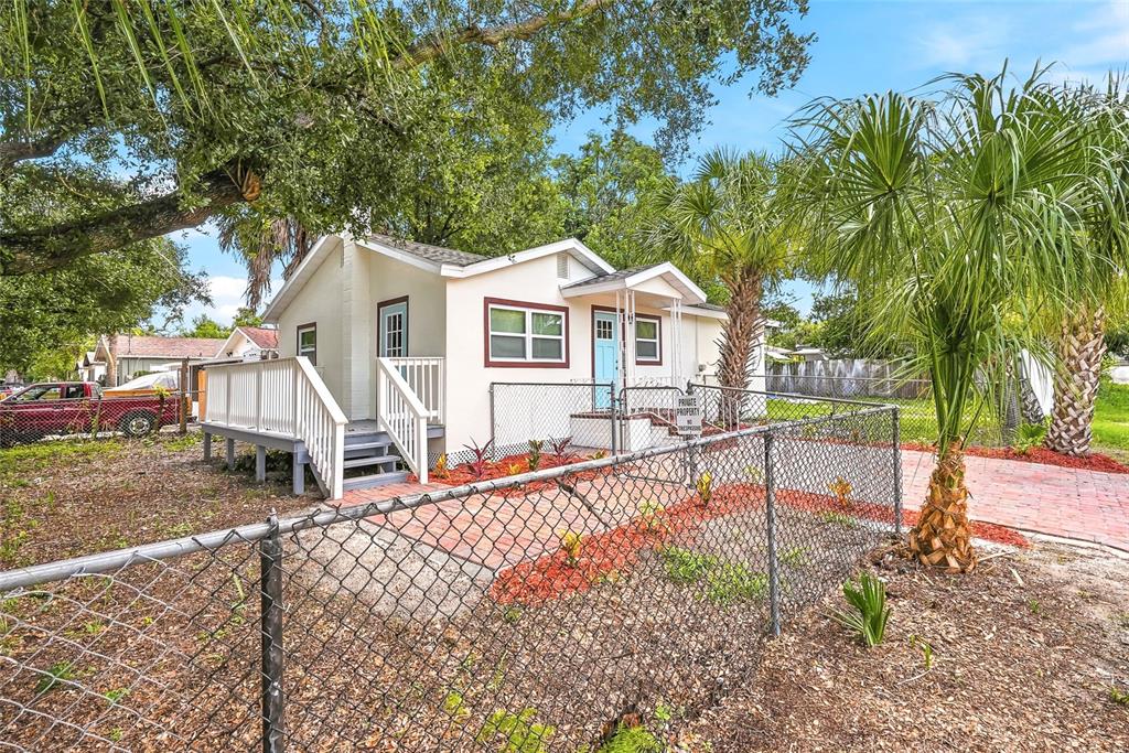 A small, light-colored house with a wooden deck and a chain-link fence in front — 1002 E SEWARD STREET, TAMPA, FL