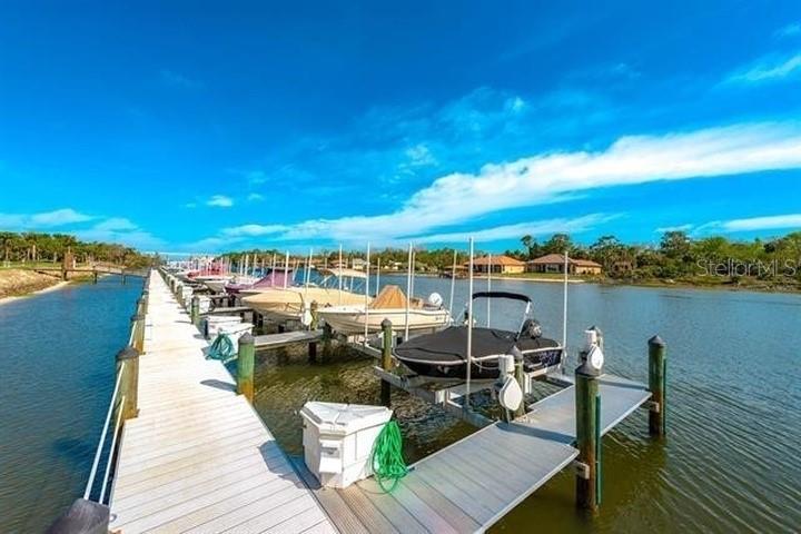 A wooden dock extends into a canal with several boats moored in boat lifts — 700 CANOPY WALK LANE UNIT 734, PALM COAST, FL
