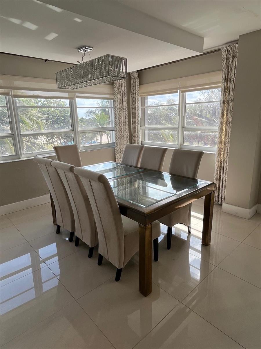 A dining room features a glass-topped wooden table, six upholstered chairs, and a rectangular chandelier — 133 N Pompano Beach Boulevard # 211, Pompano Beach FL 33062, POMPANO BEACH, FL