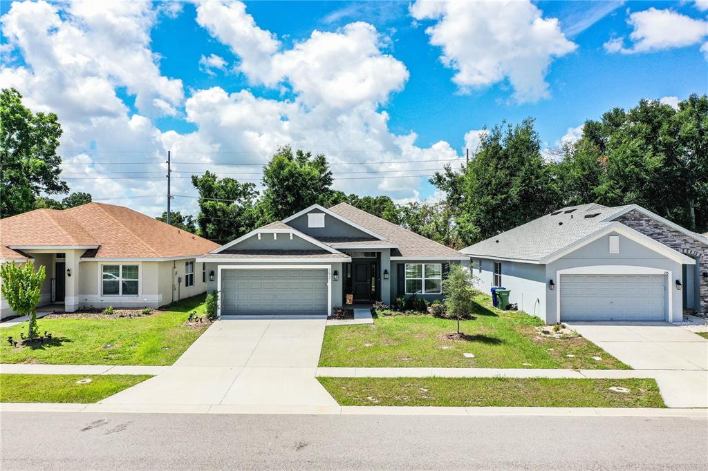 A street-level view of three suburban single-story houses with driveways and lawns under a sky — 292 KRENSON BAY LOOP, WINTER HAVEN, FL