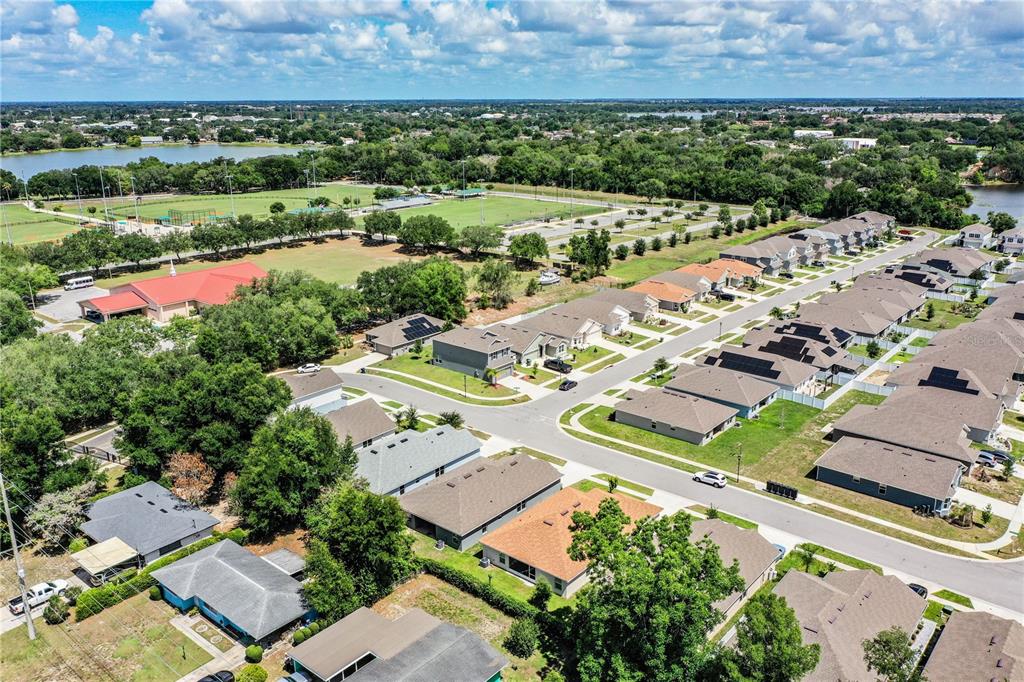 An aerial view of a suburban neighborhood featuring houses, green spaces, and a nearby park — 292 KRENSON BAY LOOP, WINTER HAVEN, FL