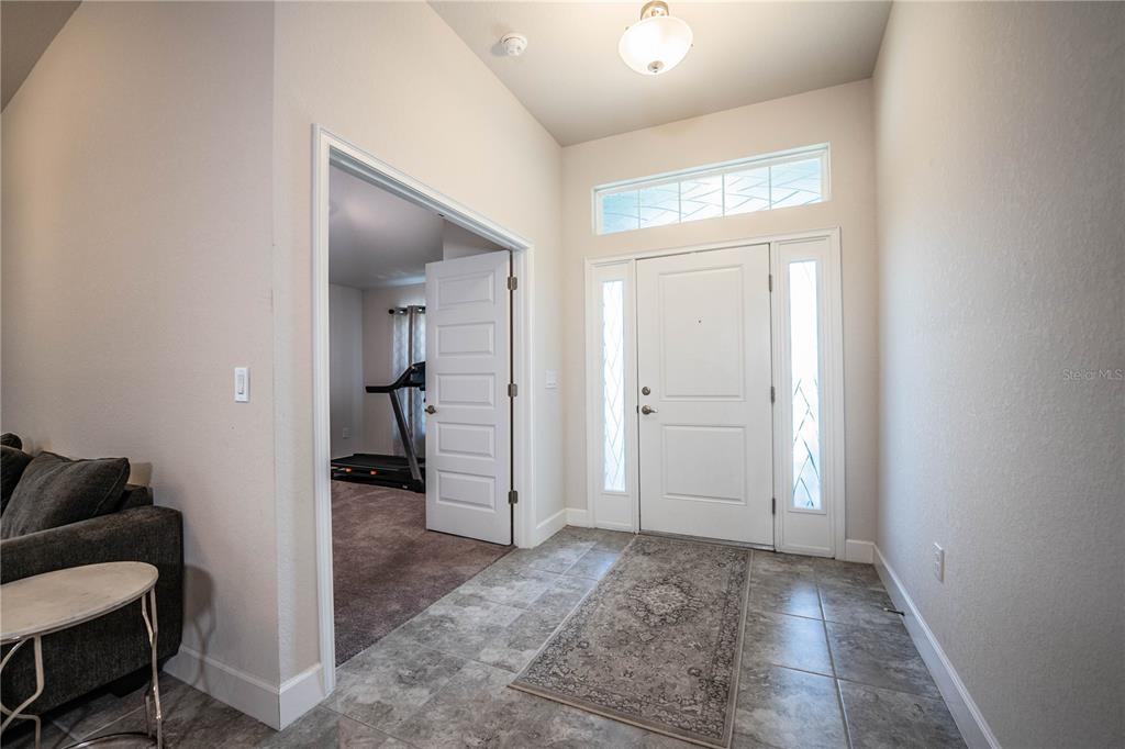 An entryway with tile flooring, a white front door with sidelights, and a doorway to a room — 292 KRENSON BAY LOOP, WINTER HAVEN, FL