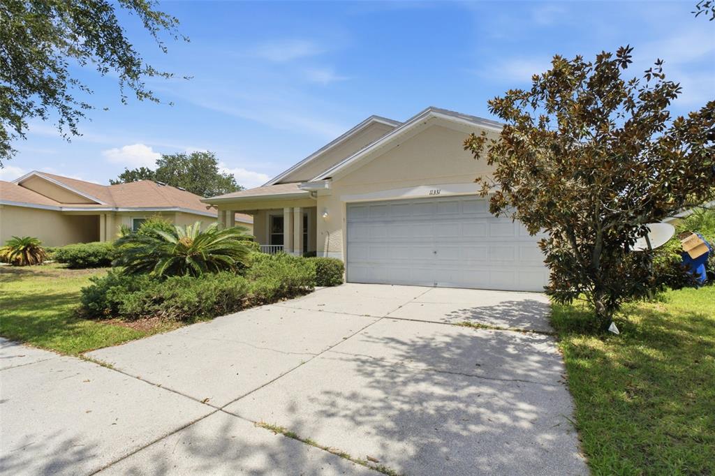 A single-story house with a beige exterior, a two-car garage, and a concrete driveway — 11331 COCONUT ISLAND DRIVE, RIVERVIEW, FL