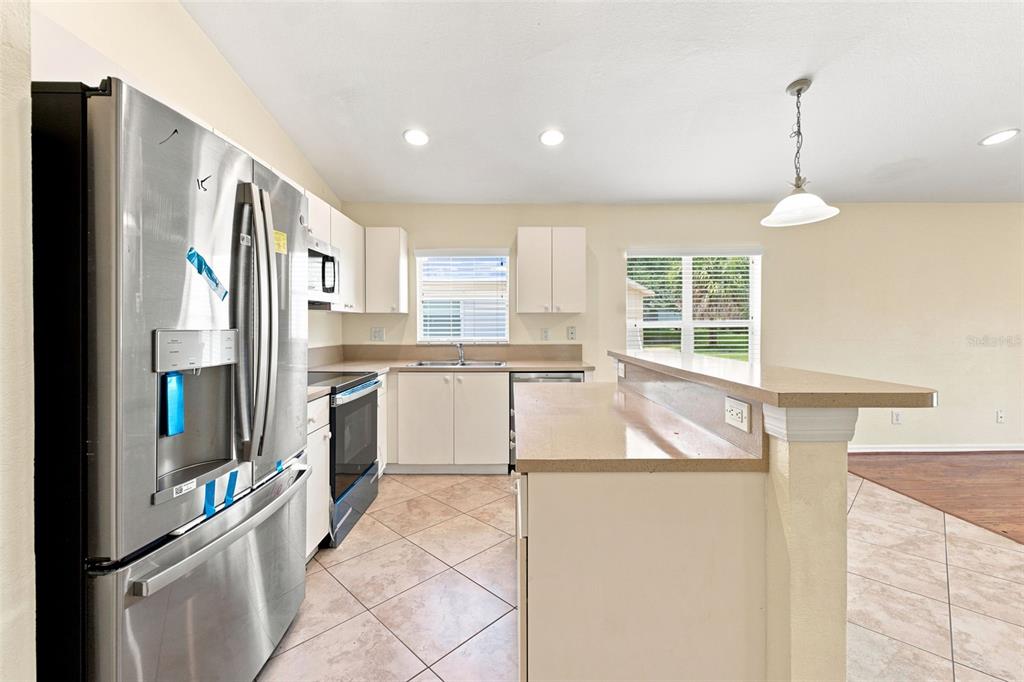 A home office with a desk, leather chair, large bookshelf, and window overlooking a yard — 11331 COCONUT ISLAND DRIVE, RIVERVIEW, FL