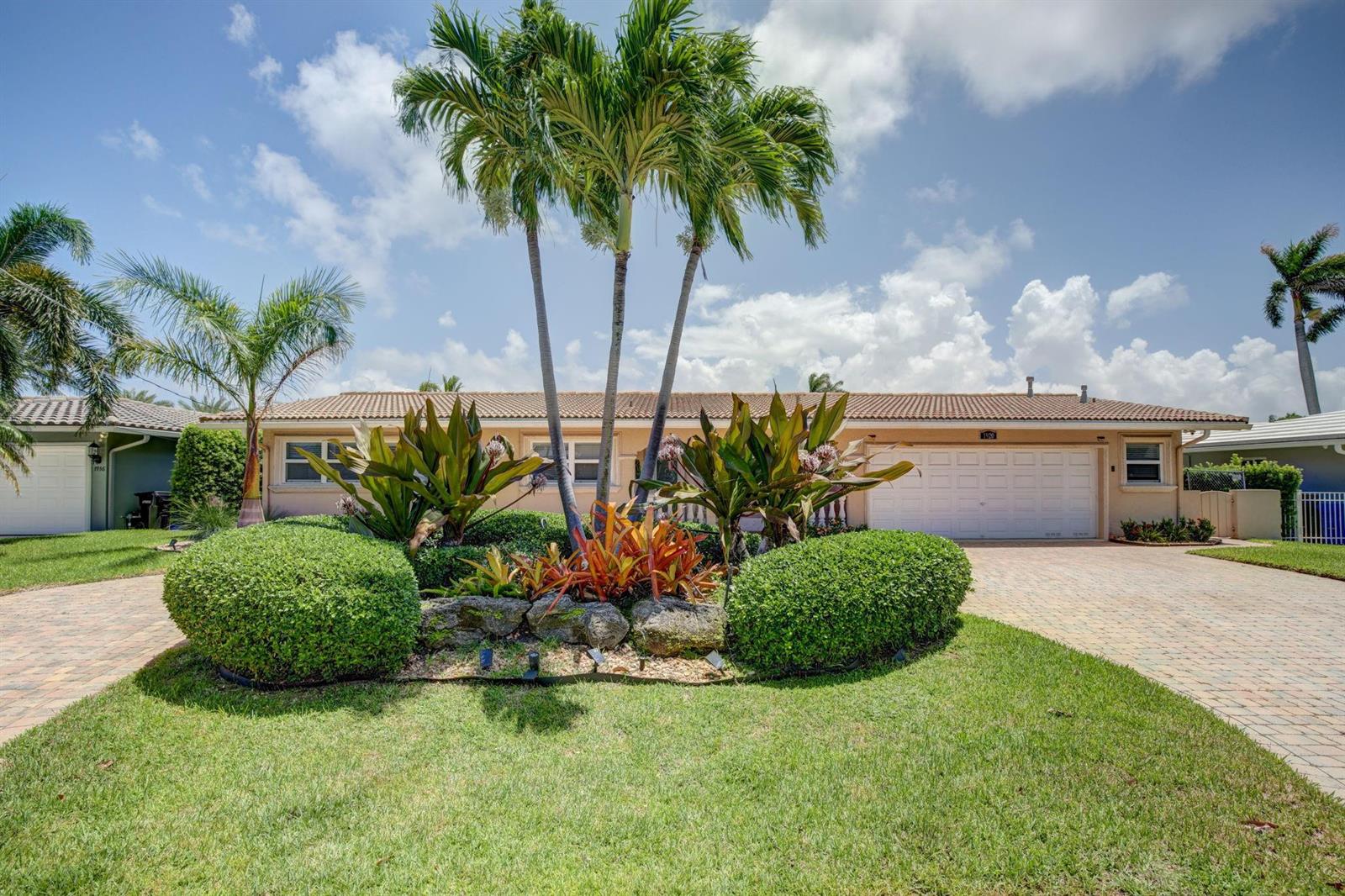 A single-story house with a paved driveway, palm trees, and a landscaped front garden — 1920 Waters Edge, Pompano Beach FL 33062, POMPANO BEACH, FL