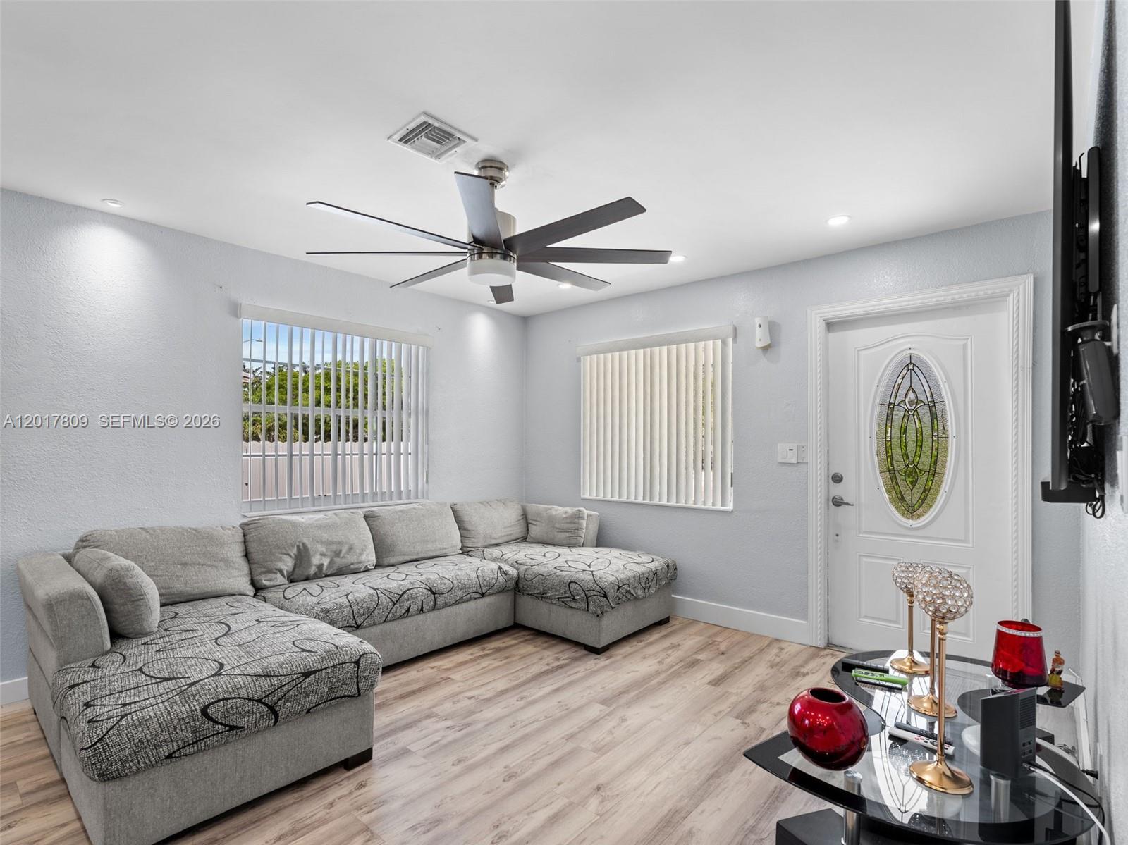 A living room features a gray sectional sofa, wood-look flooring, and a ceiling fan — 6432 Perry St, Hollywood FL 33024, HOLLYWOOD, FL