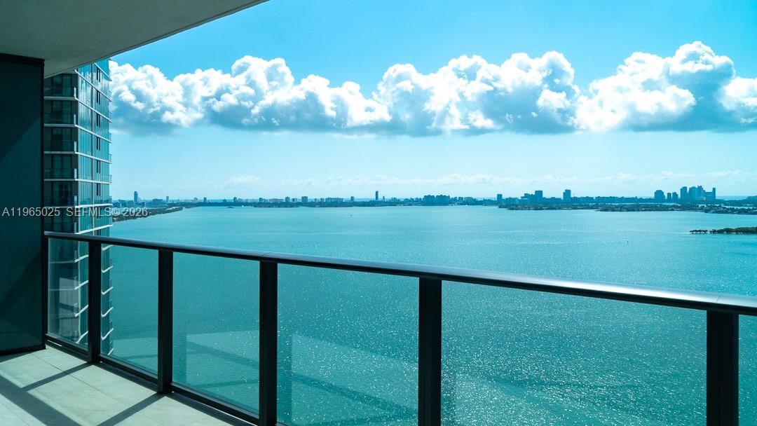 A balcony with a glass railing overlooks a large body of water and a city skyline — 650 NE 32nd St # 2105, Miami FL 33137, MIAMI, FL