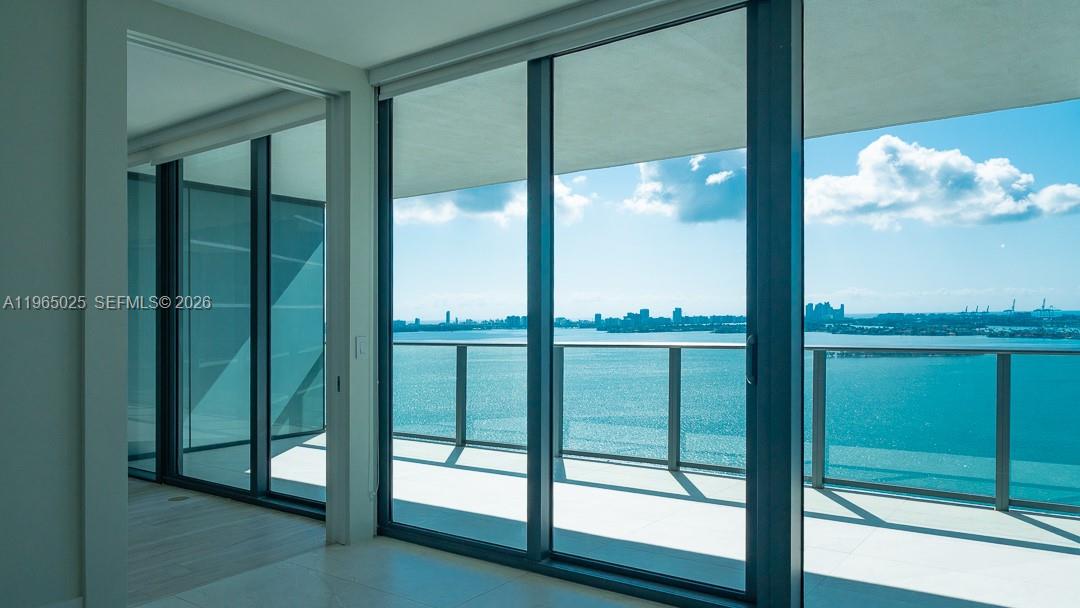 A room with floor-to-ceiling glass doors opening to a balcony overlooking a bay — 650 NE 32nd St # 2105, Miami FL 33137, MIAMI, FL
