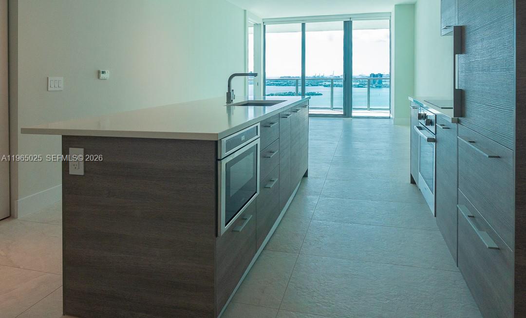 A modern kitchen features a central island with a built-in oven and water views — 650 NE 32nd St # 2105, Miami FL 33137, MIAMI, FL