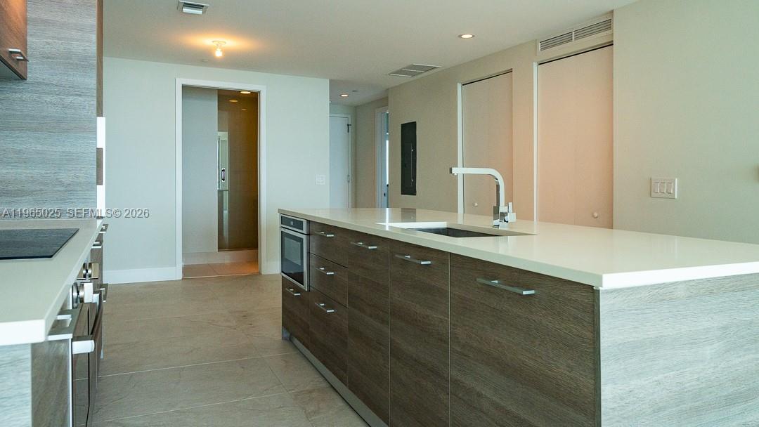 A modern kitchen features a large island with a white countertop and wood cabinetry — 650 NE 32nd St # 2105, Miami FL 33137, MIAMI, FL