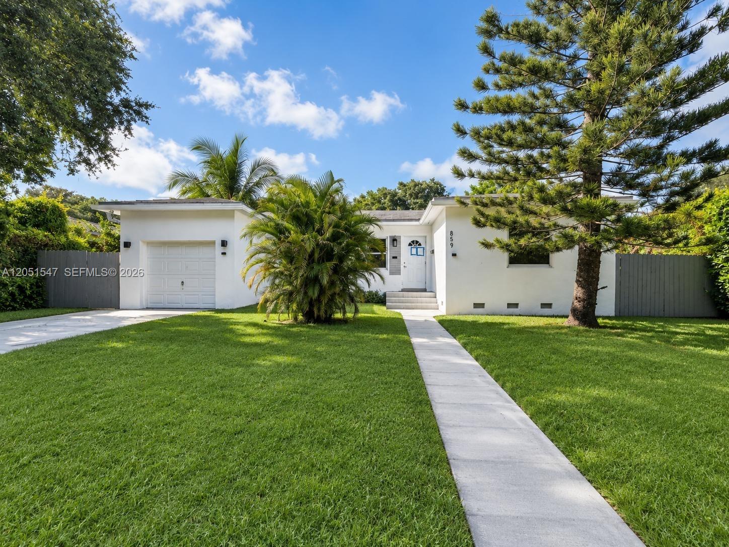 A white single-story house features a garage, a front lawn, and a concrete walkway — 859 NE 115th St, Biscayne Park FL 33161, BISCAYNE PARK, FL