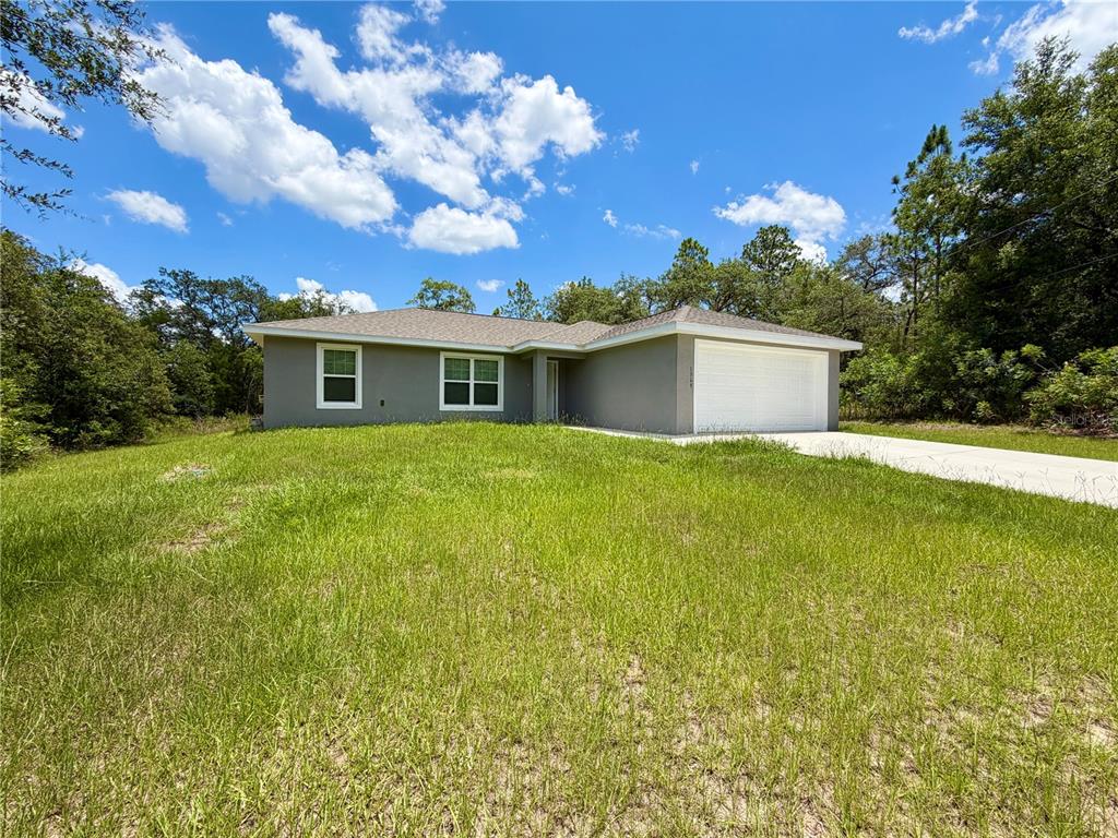 A single-story gray house with a white garage door sits on a grassy lot — 1369 W DOLORES DRIVE, CITRUS SPRINGS, FL