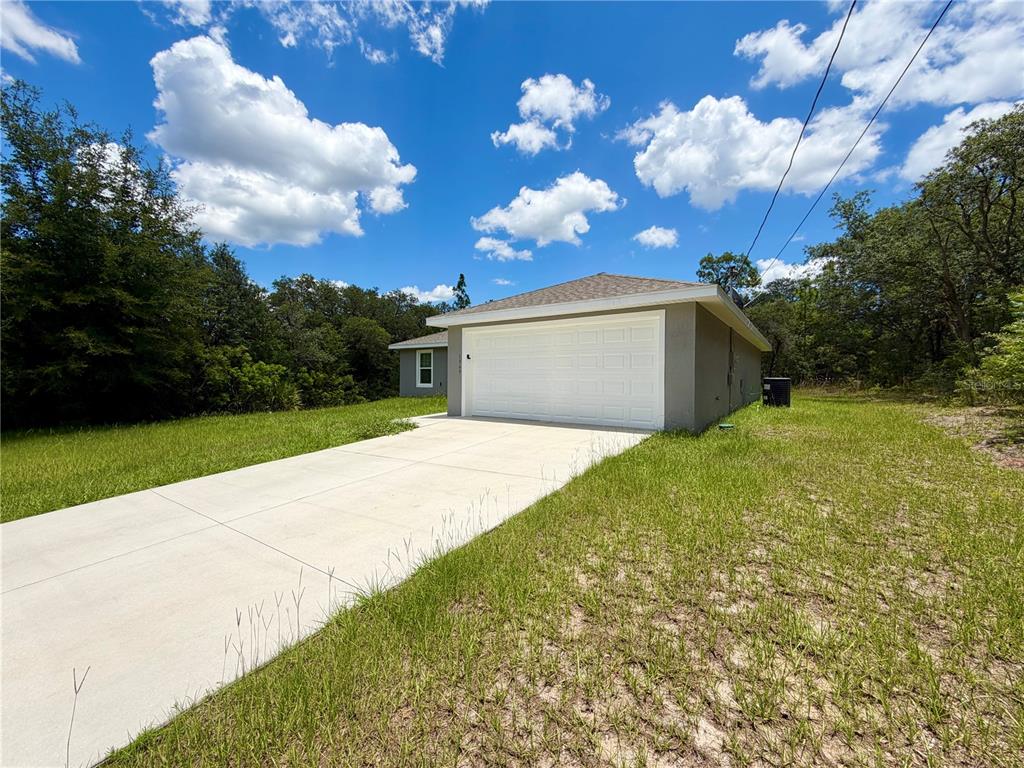 A single-story house with a white garage door and a concrete driveway sits on a lot — 1369 W DOLORES DRIVE, CITRUS SPRINGS, FL