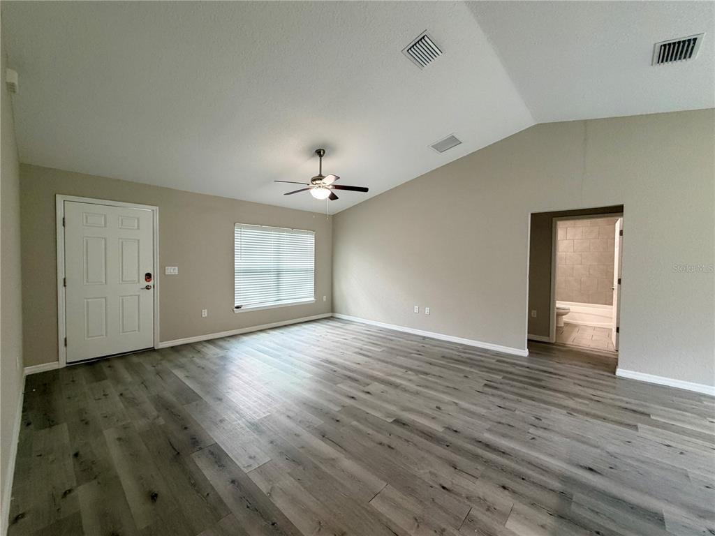 An empty room with vaulted ceilings, gray wood-look flooring, a ceiling fan, and a doorway — 1369 W DOLORES DRIVE, CITRUS SPRINGS, FL