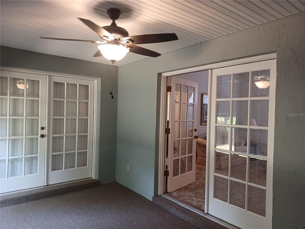 A covered patio features a ceiling fan, gray textured walls, and two sets of French doors — 805 VELMA COURT, TAVARES, FL