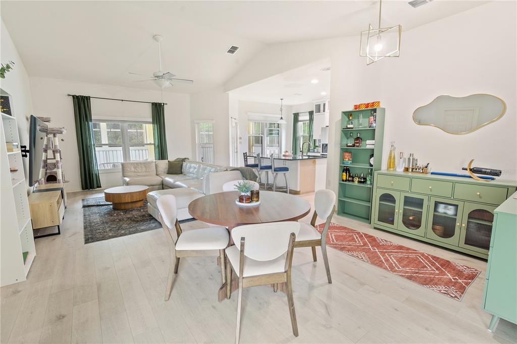 An open-concept living and dining area features light wood flooring, a sectional sofa, and furniture — 3818 SERENADE LANE UNIT 3818, LAKELAND, FL