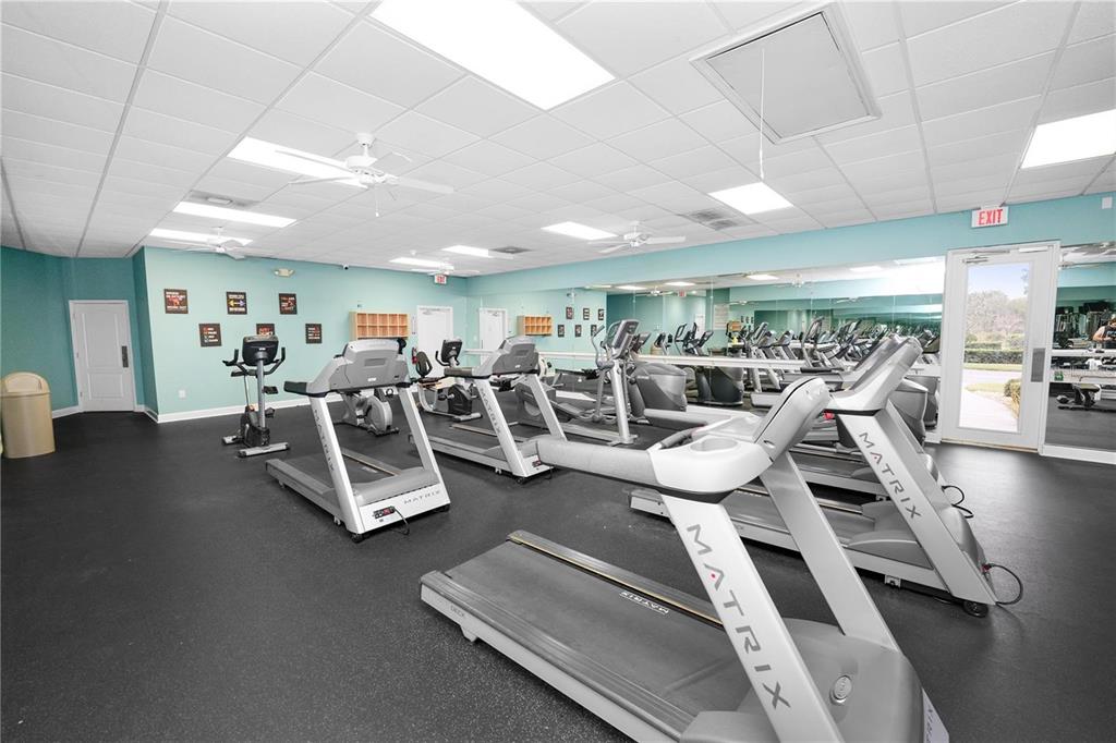 A gym room features multiple Matrix treadmills, a mirrored wall, and a drop ceiling — 3818 SERENADE LANE UNIT 3818, LAKELAND, FL
