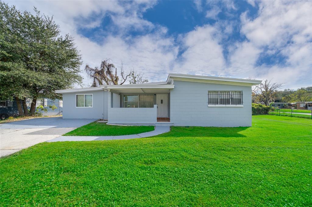 A single-story gray house with a flat roof, a front porch, and a grassy lawn — 1213 LAWNE BOULEVARD, ORLANDO, FL