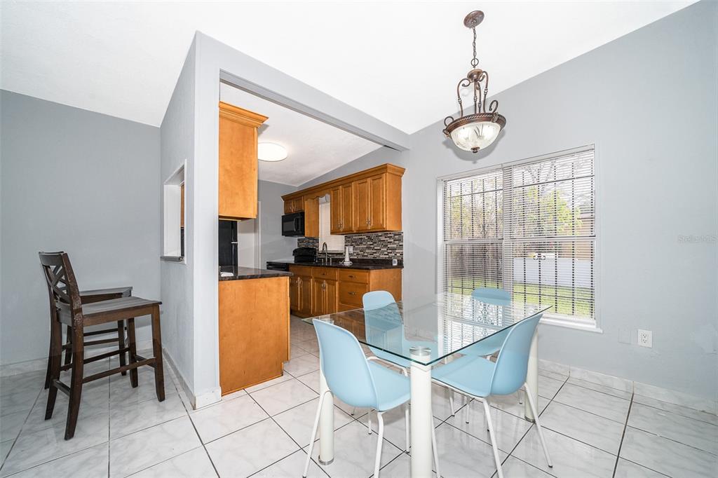 A dining area with a glass table and light blue chairs adjacent to a kitchen — 1213 LAWNE BOULEVARD, ORLANDO, FL