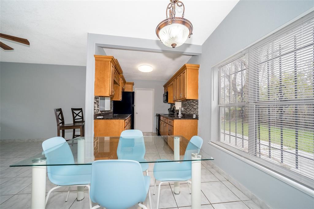 A dining area with a glass table and blue chairs sits adjacent to a kitchen — 1213 LAWNE BOULEVARD, ORLANDO, FL