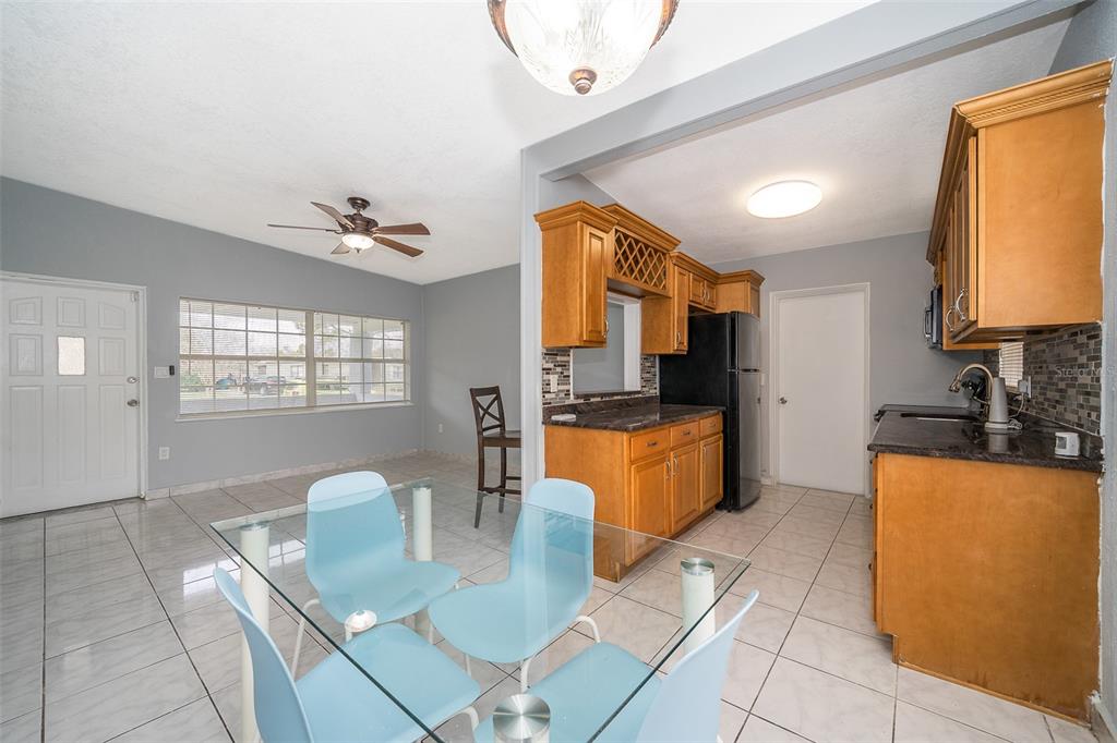 A dining area with a glass table and blue chairs sits adjacent to a kitchen — 1213 LAWNE BOULEVARD, ORLANDO, FL