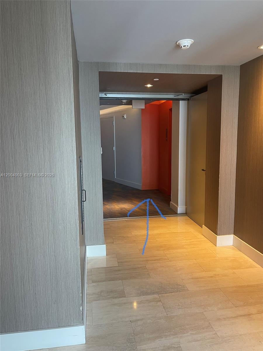 A hallway with light-colored tile flooring leads into a room with dark wood-look flooring — 4111 S Ocean Dr # 3411, Hollywood FL 33019, HOLLYWOOD, FL