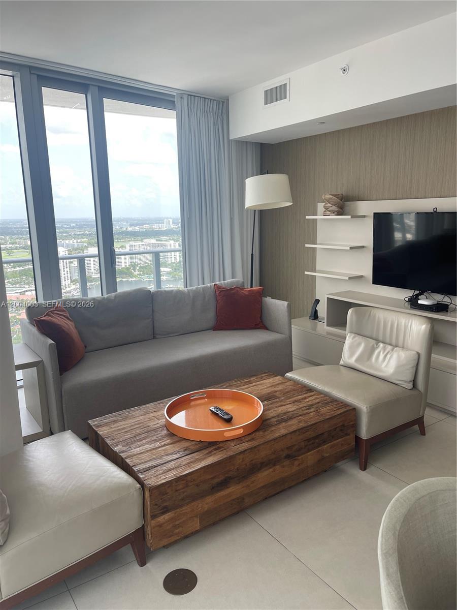 A living room features a gray sofa, a wooden coffee table, and floor-to-ceiling windows — 4111 S Ocean Dr # 3411, Hollywood FL 33019, HOLLYWOOD, FL
