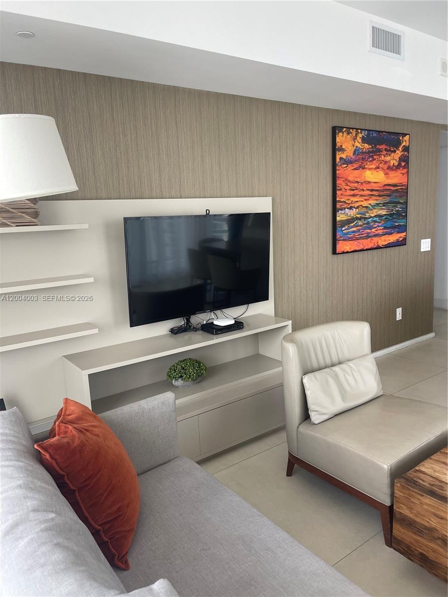 A living room features a wall-mounted television, open shelving, and a textured accent wall — 4111 S Ocean Dr # 3411, Hollywood FL 33019, HOLLYWOOD, FL