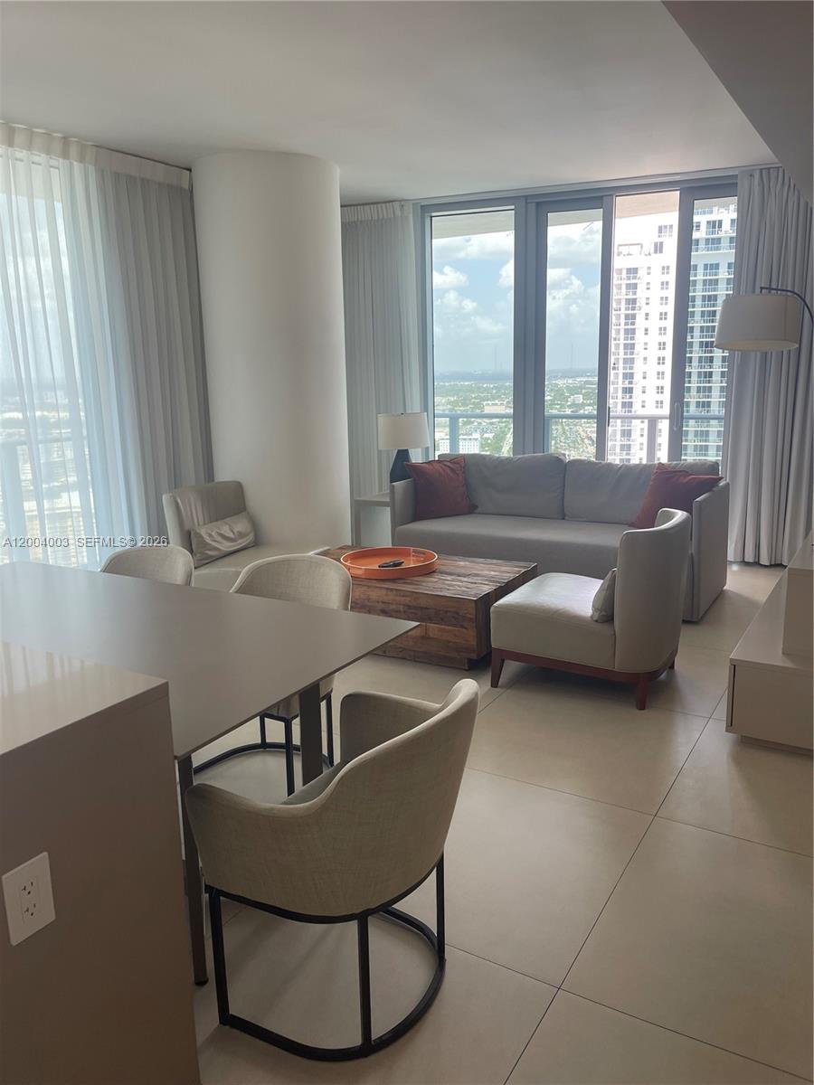 A modern living and dining area features tile floors, floor-to-ceiling windows, and city views — 4111 S Ocean Dr # 3411, Hollywood FL 33019, HOLLYWOOD, FL