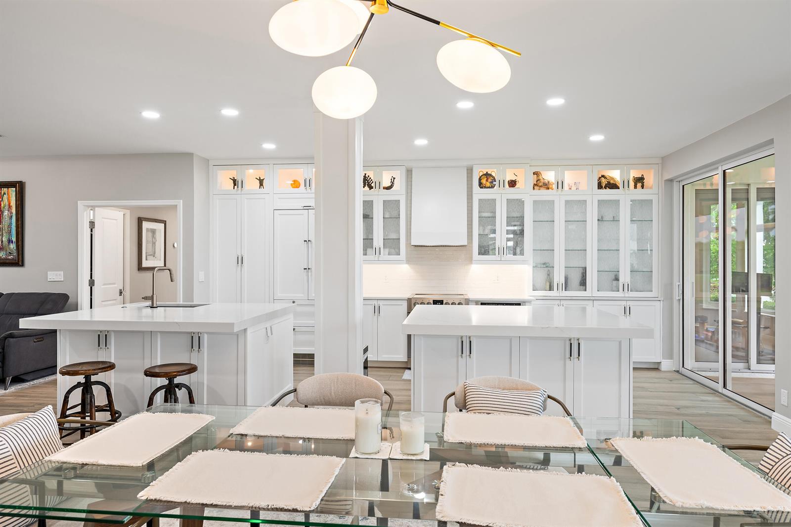 A bright kitchen features white cabinetry, two islands, and a glass-topped dining table — 316 Spyglass Way, Jupiter FL 33477, JUPITER, FL