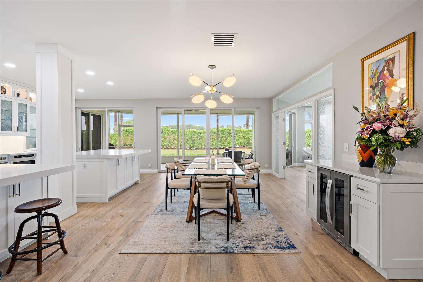 A dining area with a glass table, modern chandelier, and adjacent kitchen with white cabinetry — 316 Spyglass Way, Jupiter FL 33477, JUPITER, FL