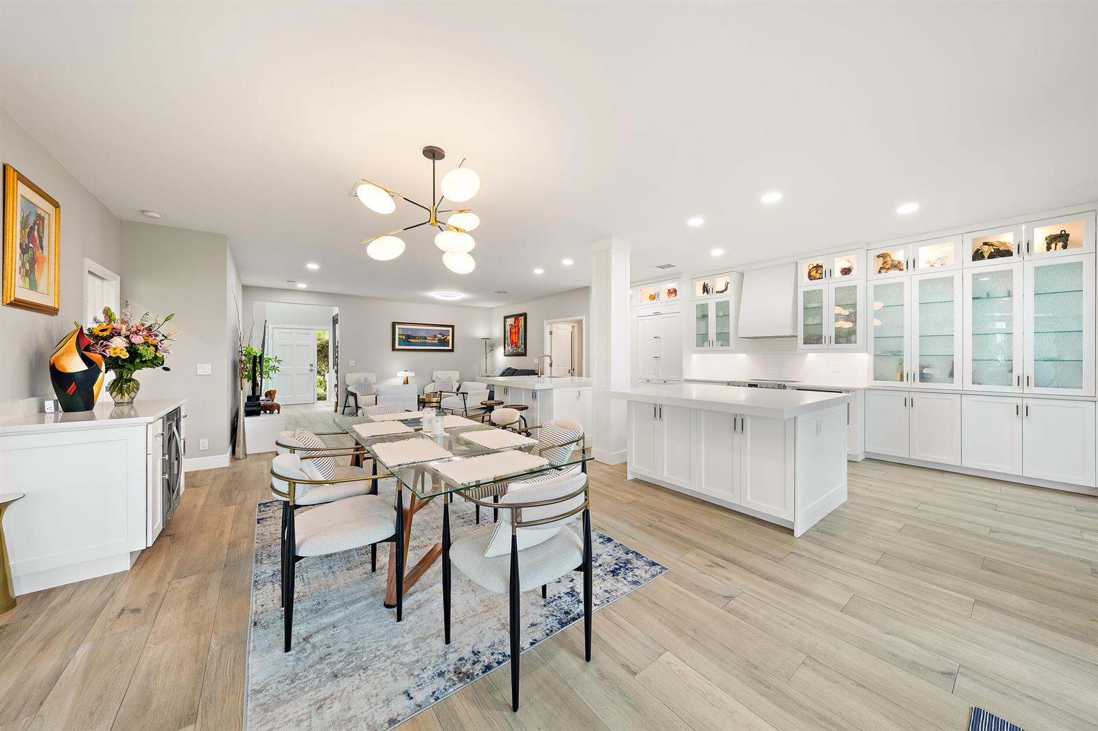 An open-concept kitchen and dining area features white cabinetry, a glass-top table, and wood flooring — 316 Spyglass Way, Jupiter FL 33477, JUPITER, FL