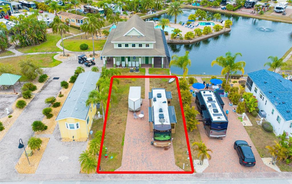 An aerial view shows a paved RV site with a motorhome and trailer near a lake — 6940 AMANDA VISTA CIRCLE, LAND O LAKES, FL