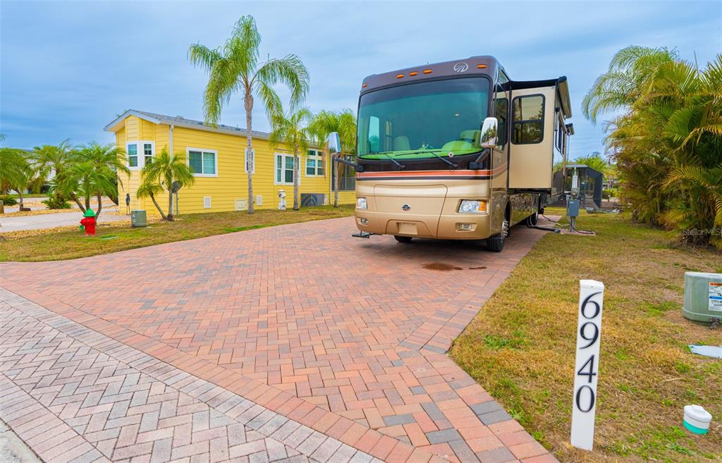A large motorhome is parked on a brick driveway next to a yellow house — 6940 AMANDA VISTA CIRCLE, LAND O LAKES, FL