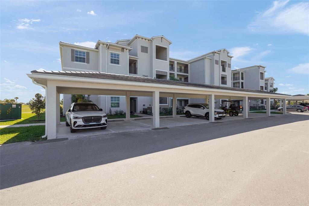 A multi-story apartment building with a covered parking structure in the foreground — 17630 OPAL SAND DRIVE UNIT 102, VENICE, FL