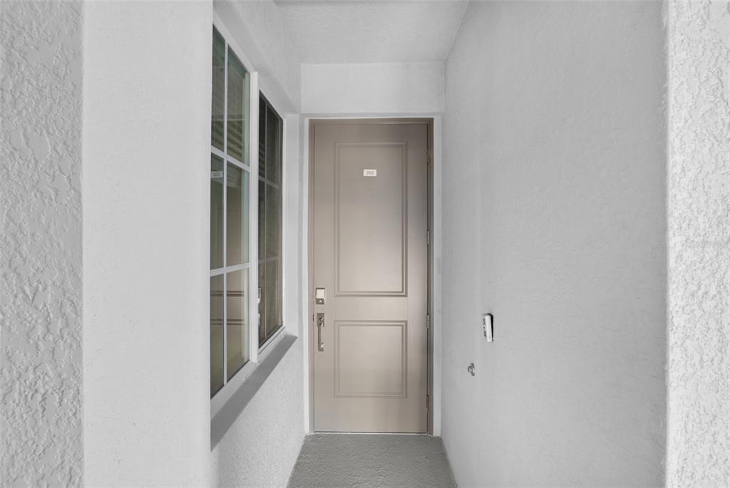 A beige front door with a window to the left in a white entryway — 17630 OPAL SAND DRIVE UNIT 102, VENICE, FL