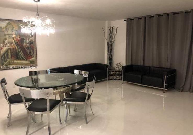 A dining area with a glass table and chairs sits beside a living room with black sofas — 9195 Collins Ave # 406, Surfside FL 33154, SURFSIDE, FL