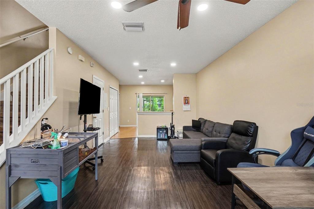 A living room with dark wood-look flooring, a gray sectional sofa, and a staircase railing — 6236 OSPREY LAKE CIRCLE, RIVERVIEW, FL