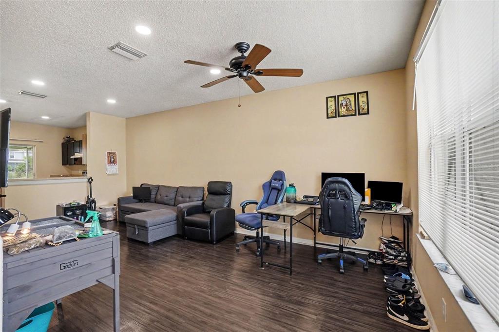 A living room with dark wood floors, a gray sectional, and a dual-desk workspace — 6236 OSPREY LAKE CIRCLE, RIVERVIEW, FL