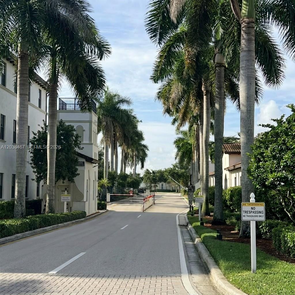 A gated entrance with palm trees lines a paved road leading to a residential complex — 11835 SW 27th St # 801, Miramar FL 33025, MIRAMAR, FL